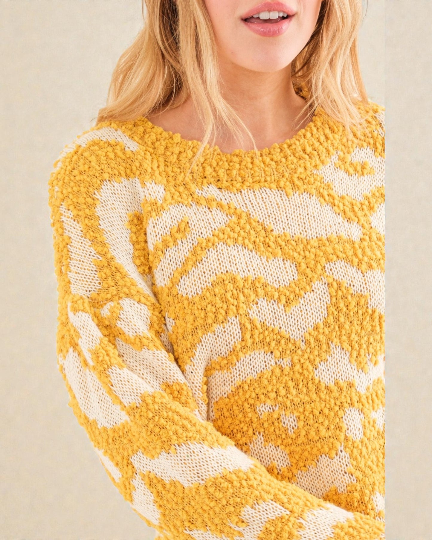 Yellow and white patterned sweater worn by a person on a beige background