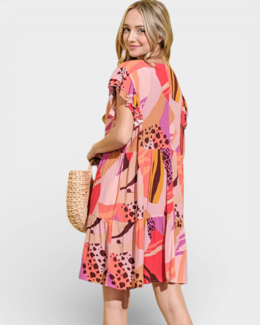 Woman wearing a colorful patterned dress holding a straw bag on a white background
