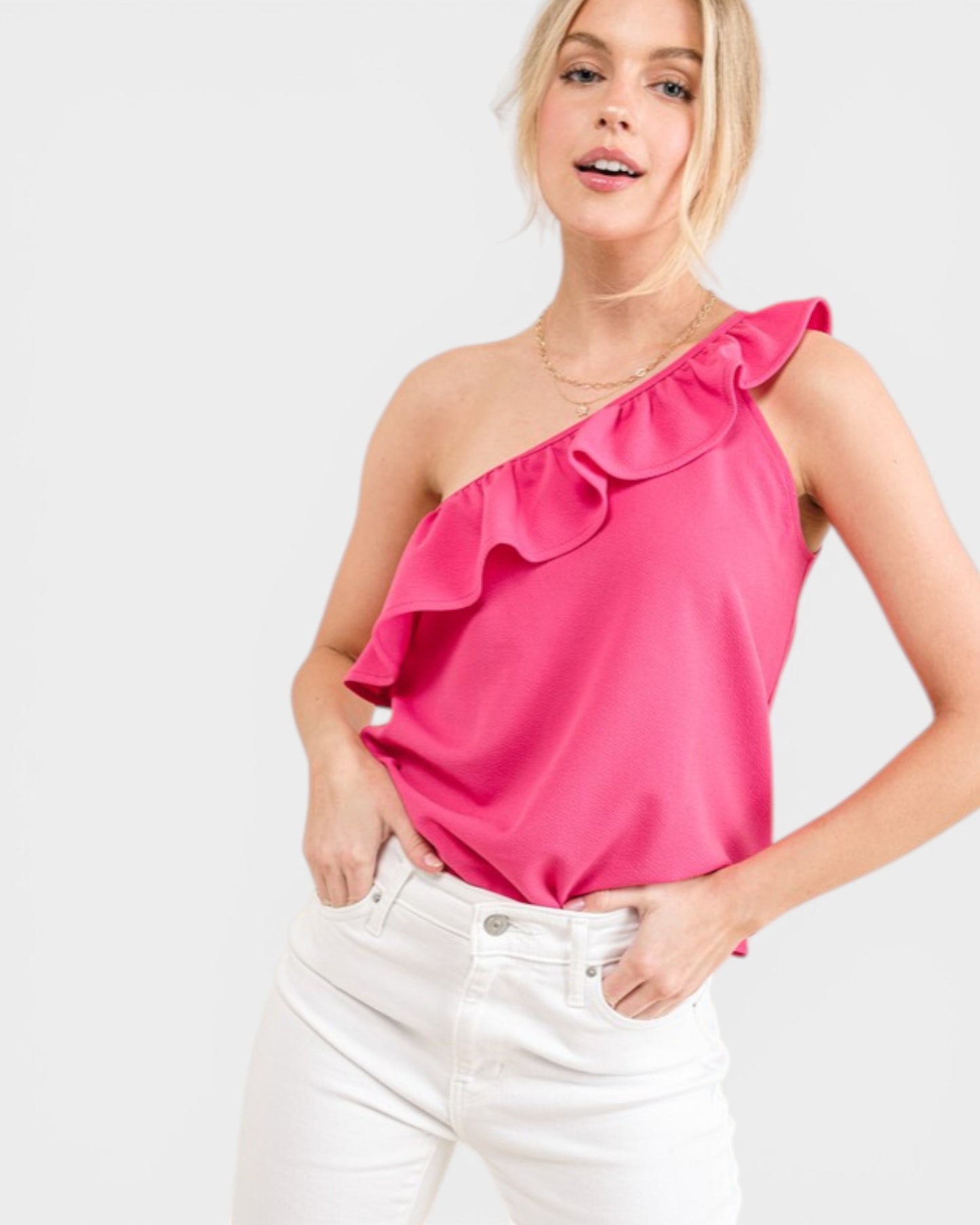 Woman wearing a bright pink one-shoulder top with ruffles on a white background