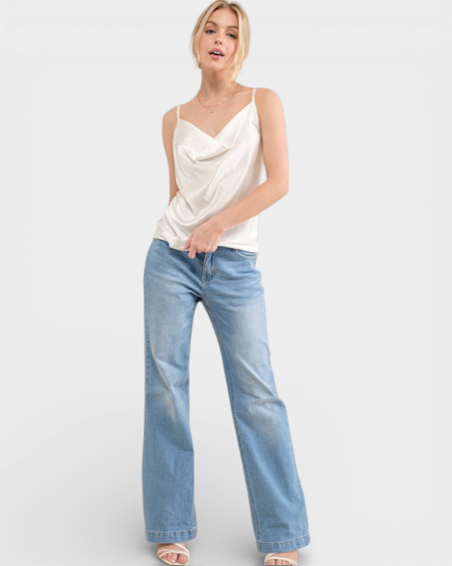 Woman wearing a white top and light blue jeans on a white background