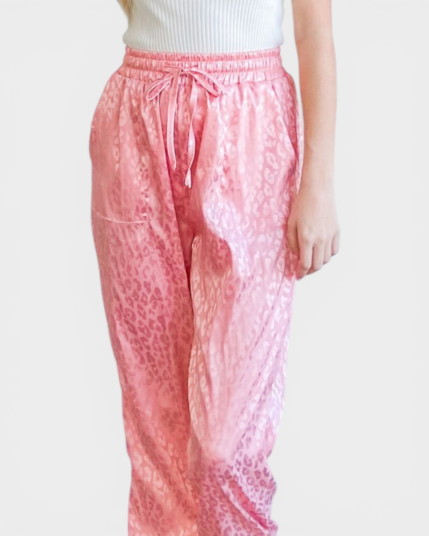 Pink leopard print pants worn by a person on a white background
