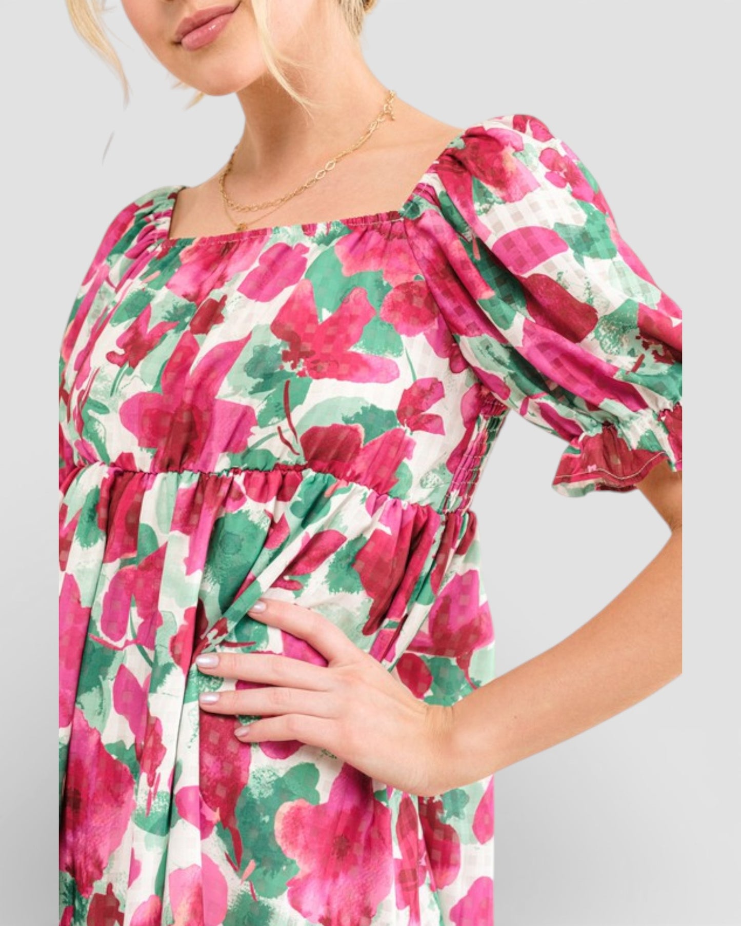 Woman wearing a floral dress with pink and green flowers on a plain background