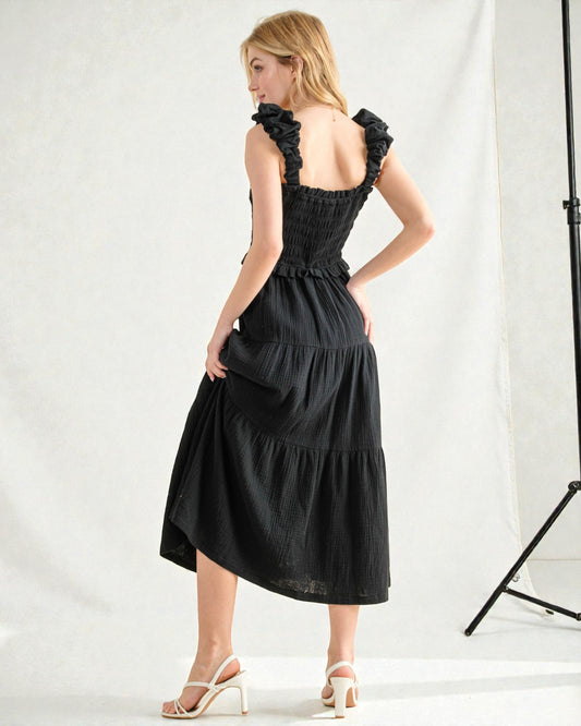 Woman wearing a black dress with ruffled straps against a white background