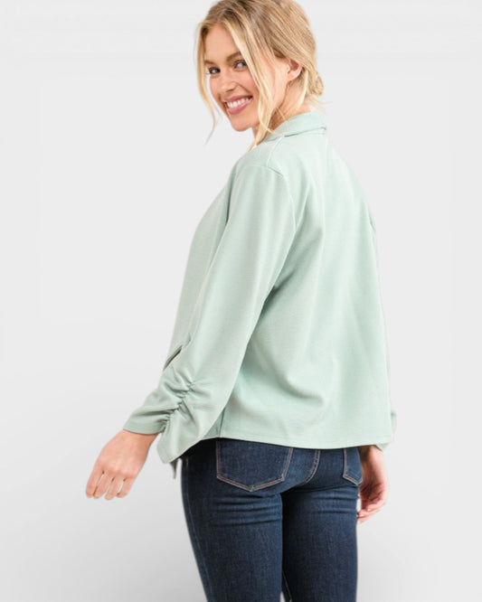 Woman wearing a light green blouse and blue jeans on a white background