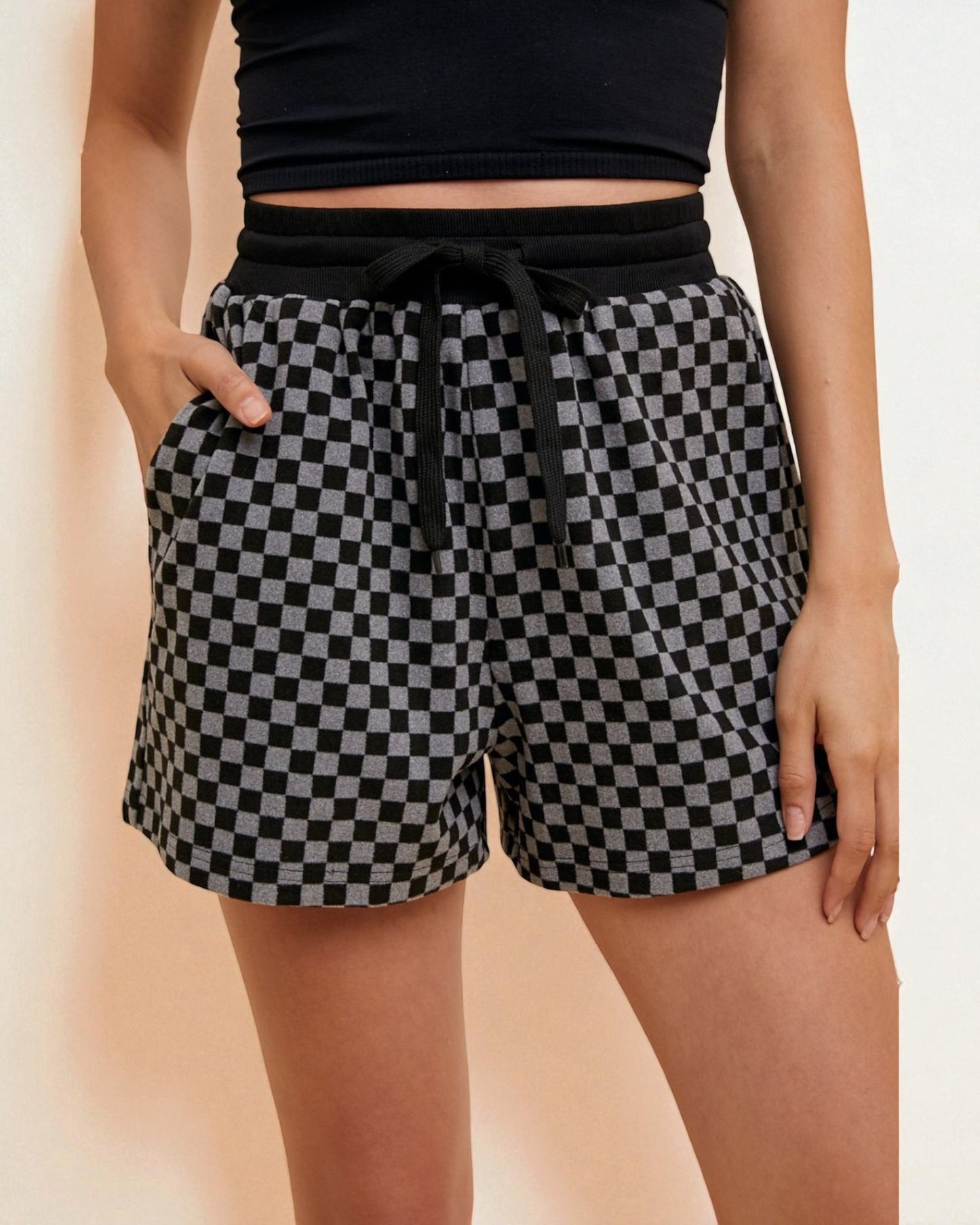 Person wearing black and white checkered shorts on a beige background