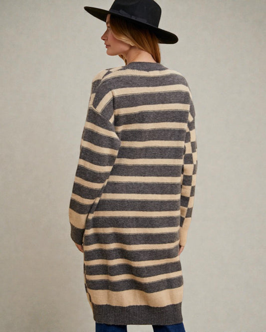 Woman wearing a long, striped sweater with a plain background