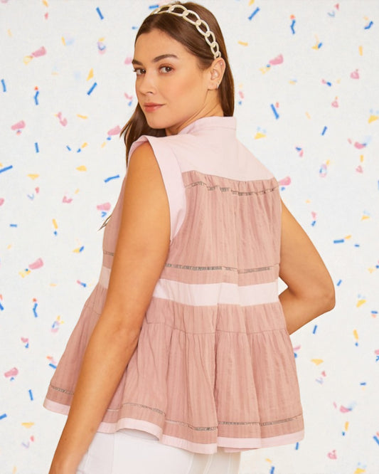 Woman wearing a pink sleeveless top with a white background and colorful confetti-like patterns.