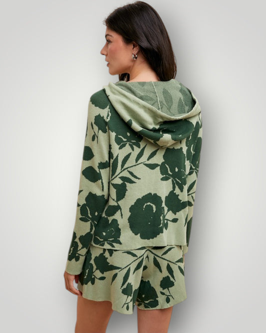 Woman wearing a green floral-patterned hoodie and skirt set against a plain background