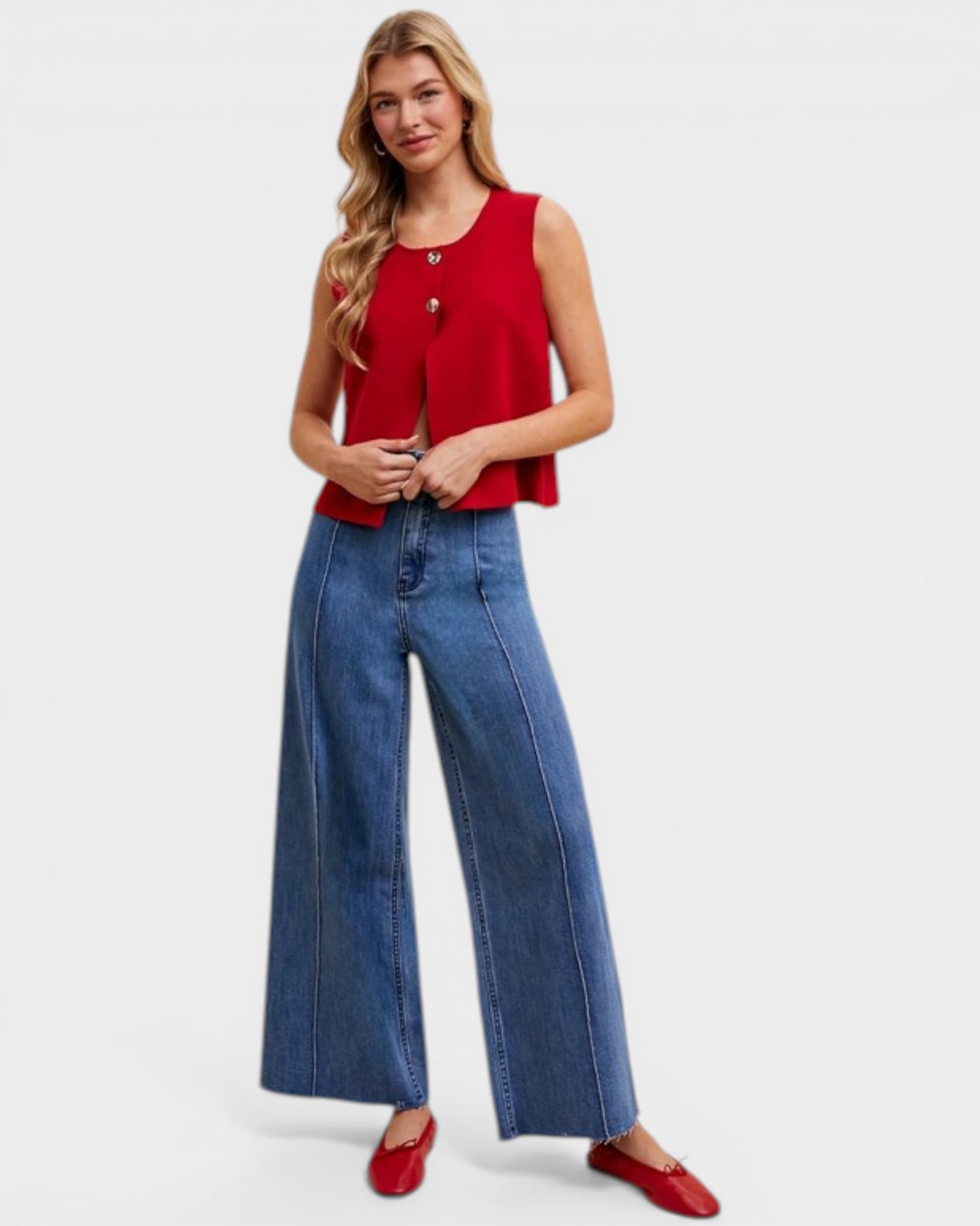 Woman wearing a red sleeveless top and blue jeans on a white background