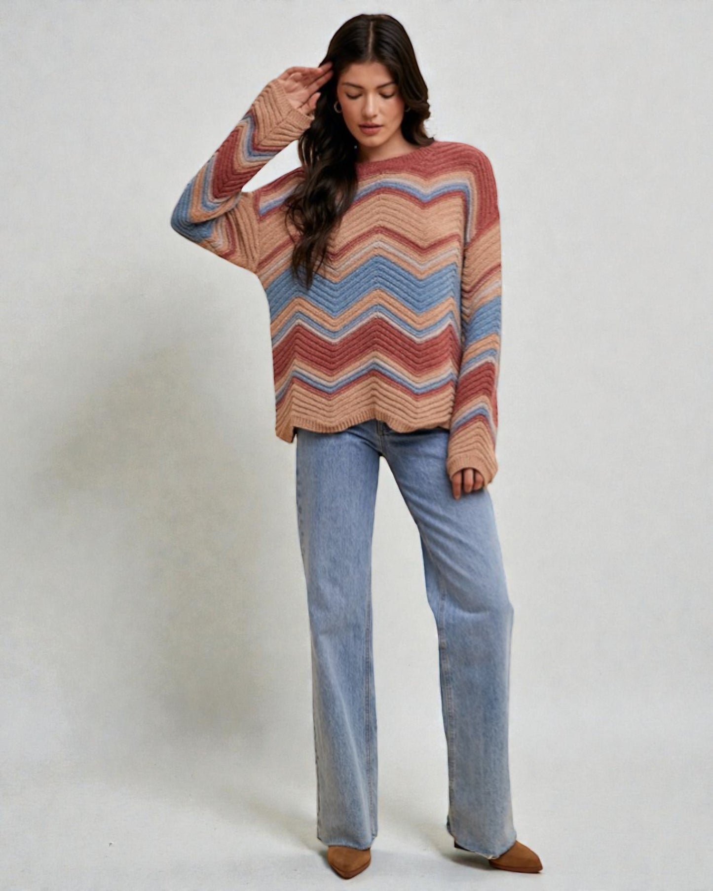 Woman wearing a colorful striped sweater and blue jeans on a white background