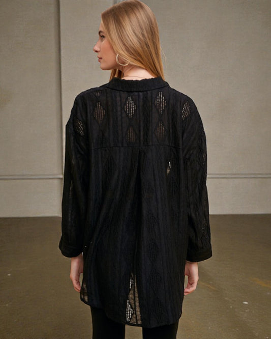 Woman wearing a black lace dress against a plain background