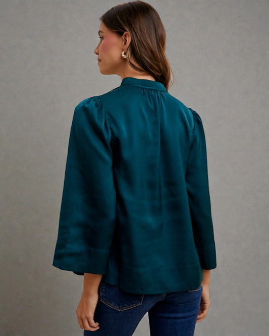 Woman wearing a teal blouse against a gray background