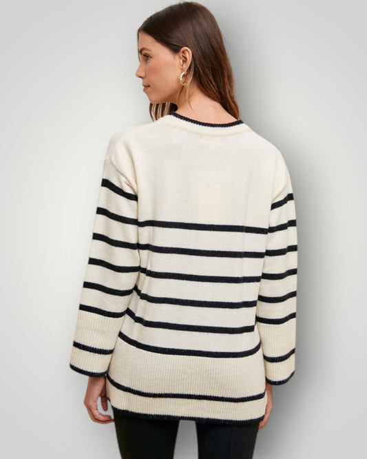 Woman wearing a cream and navy striped sweater against a plain background
