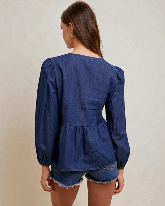 Woman wearing a blue denim blouse with puffed sleeves on a beige background