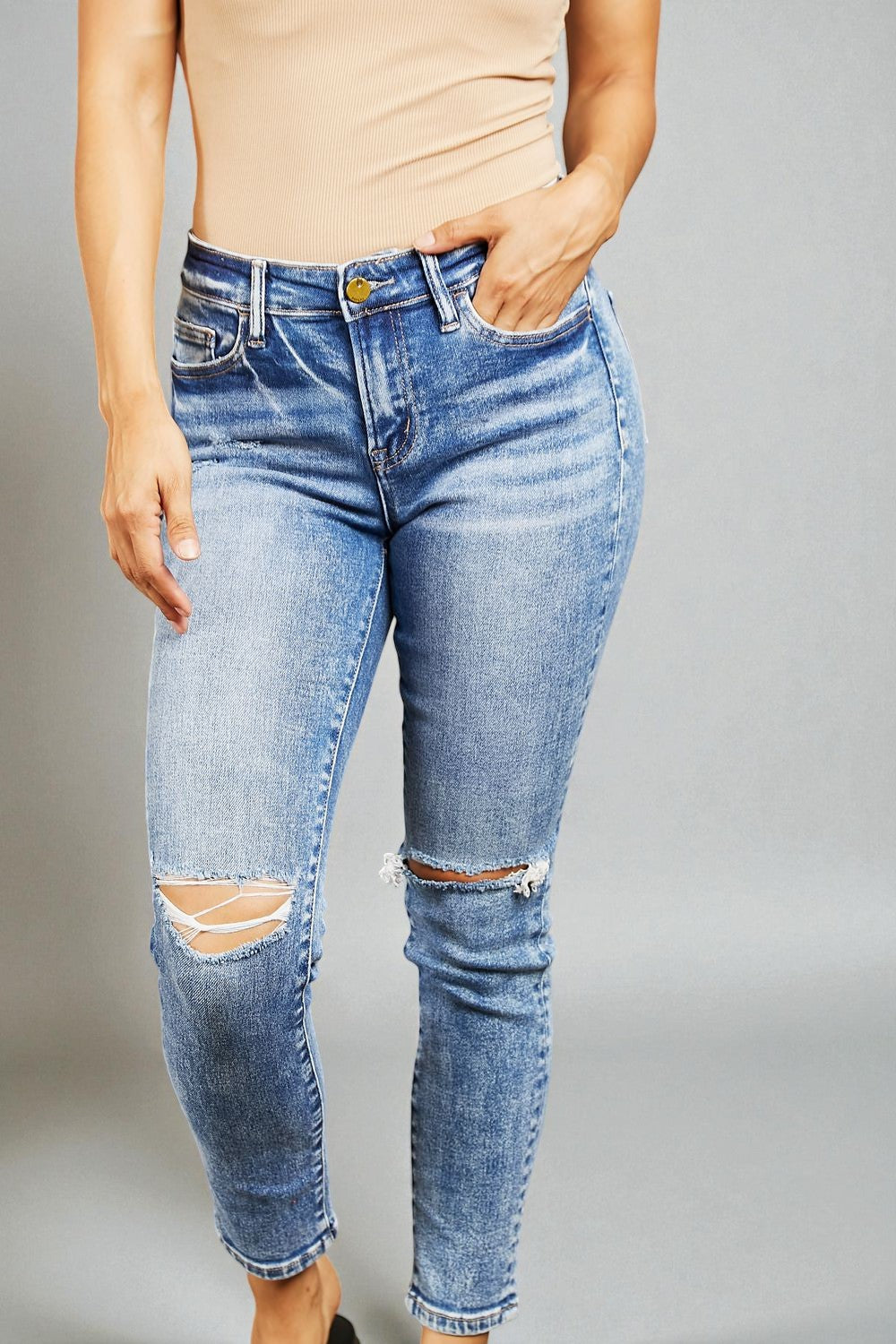 Person wearing blue ripped jeans on a gray background