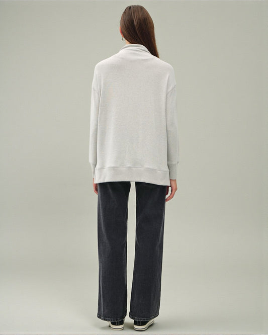 Person wearing a white sweater and dark pants on a plain background