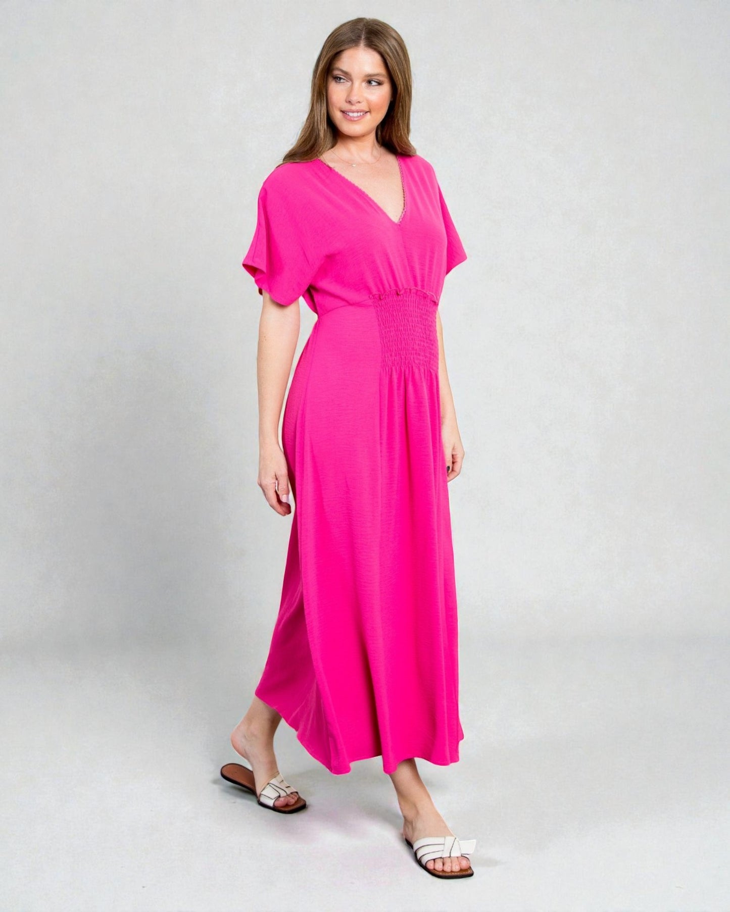 Woman wearing a bright pink dress on a gray background