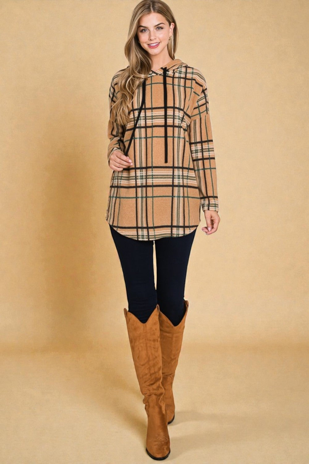 Woman wearing a plaid top and knee-high boots on a beige background