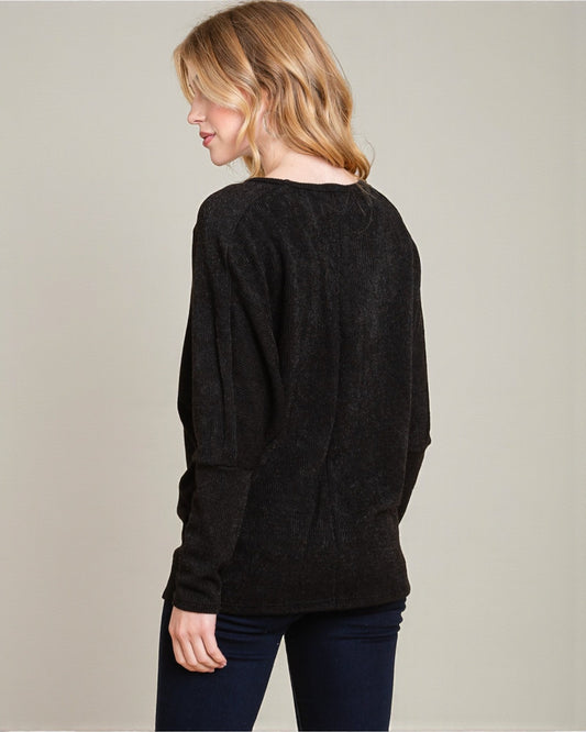 Woman wearing a black sweater against a plain background