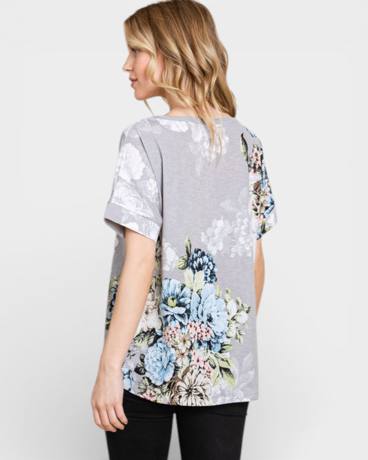 Woman wearing a gray t-shirt with floral designs on a plain background