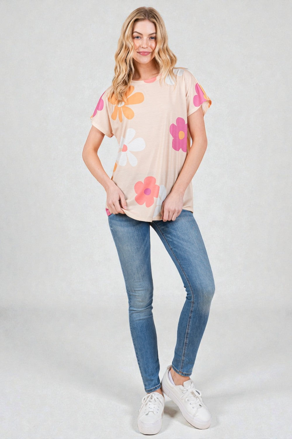 Woman wearing a floral t-shirt and jeans on a plain background