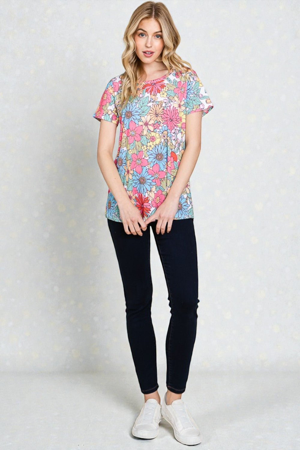 Woman wearing a colorful floral t-shirt and black pants on a white background