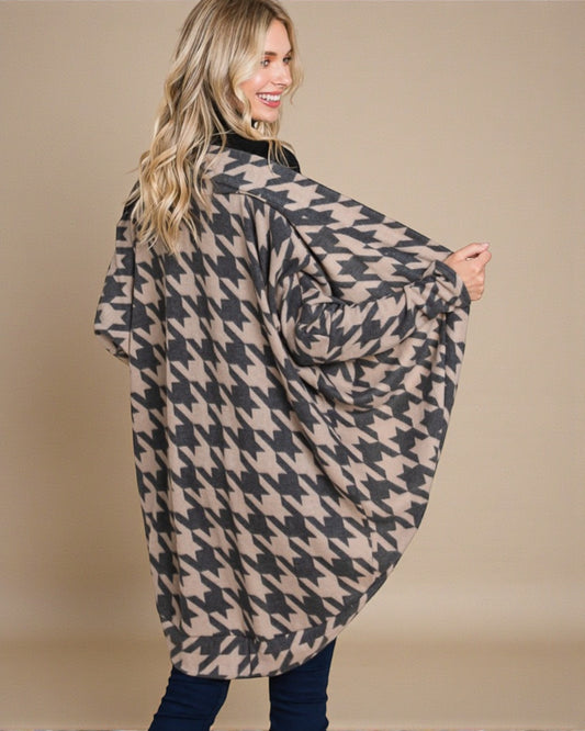 Woman wearing a houndstooth patterned poncho against a beige background