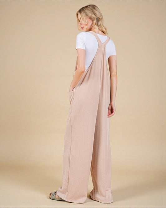 Woman wearing a beige overalls with a plain background