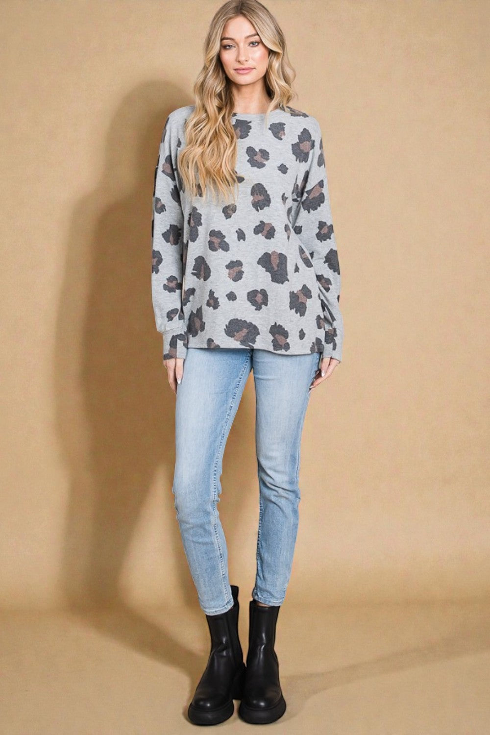 Woman wearing a patterned sweater and light blue jeans against a beige background