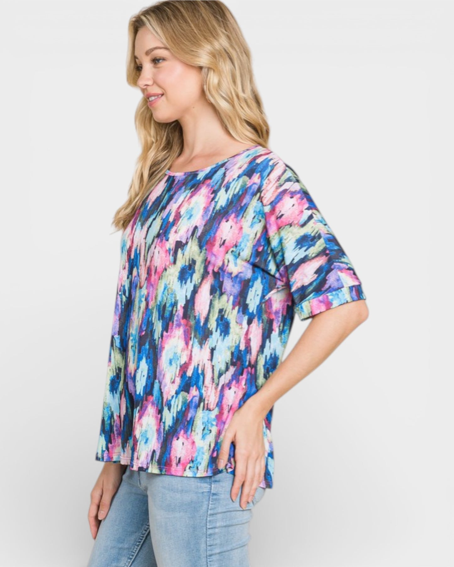 Woman wearing a colorful floral blouse against a plain background