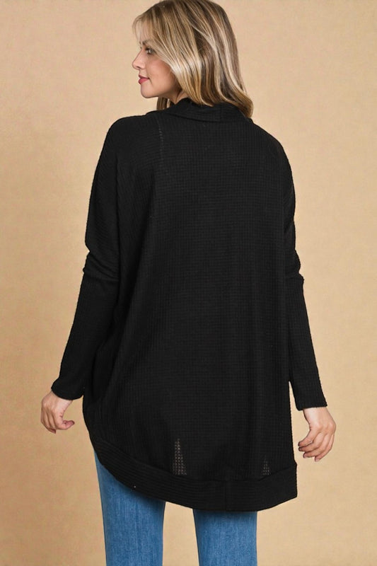 Woman wearing a black long-sleeve top against a beige background