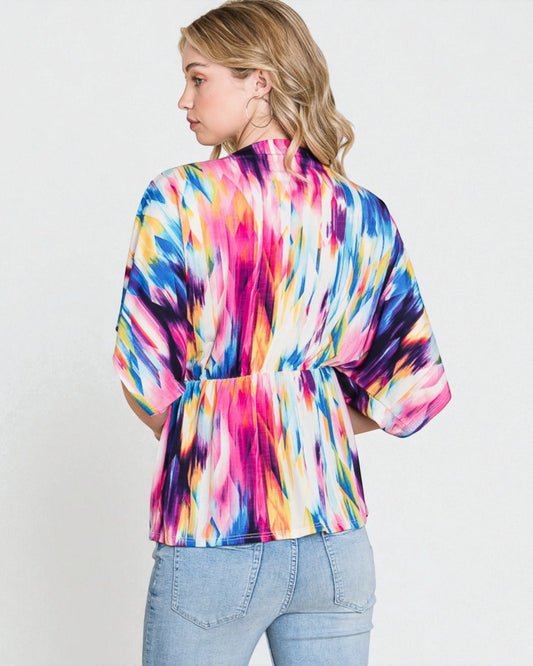 Woman wearing a colorful tie-dye shirt against a white background