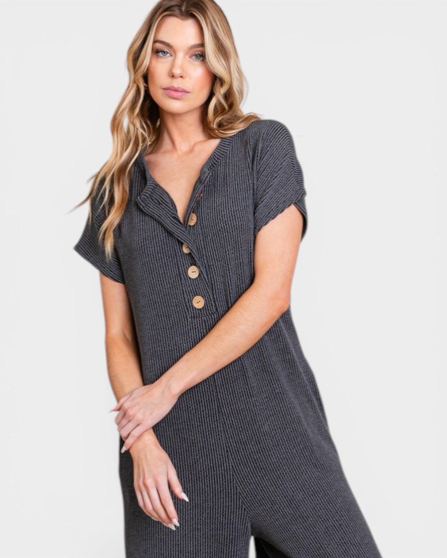 Woman wearing a gray button-up jumpsuit on a light gray background