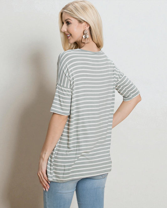 Woman wearing a striped shirt and jeans against a plain background