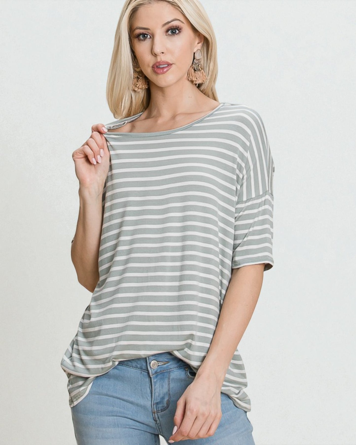 Woman wearing a gray and white striped shirt with a plain background