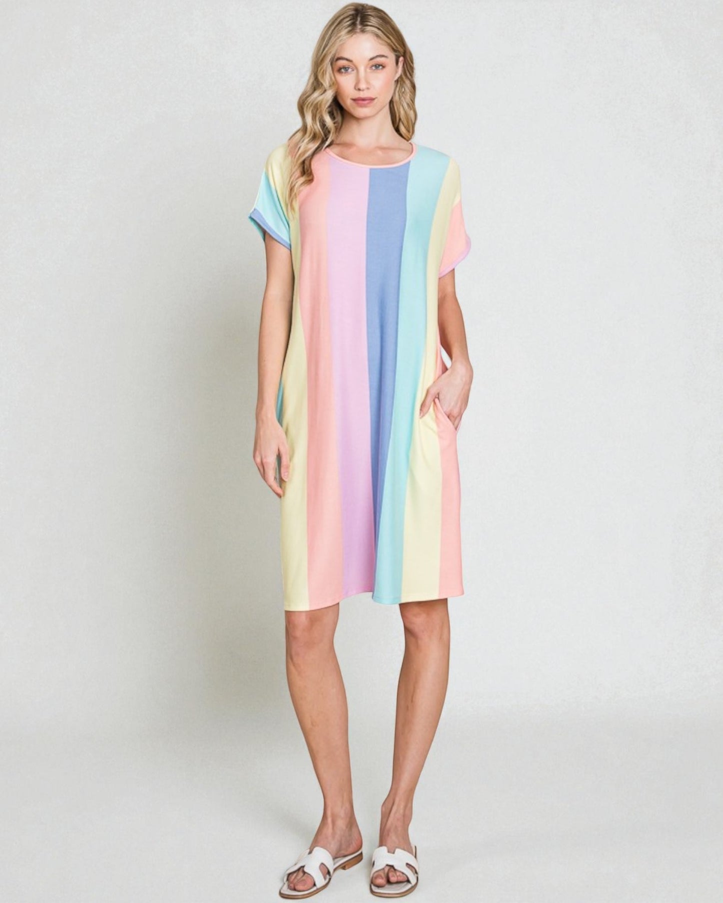 Woman wearing a colorful striped dress on a plain background