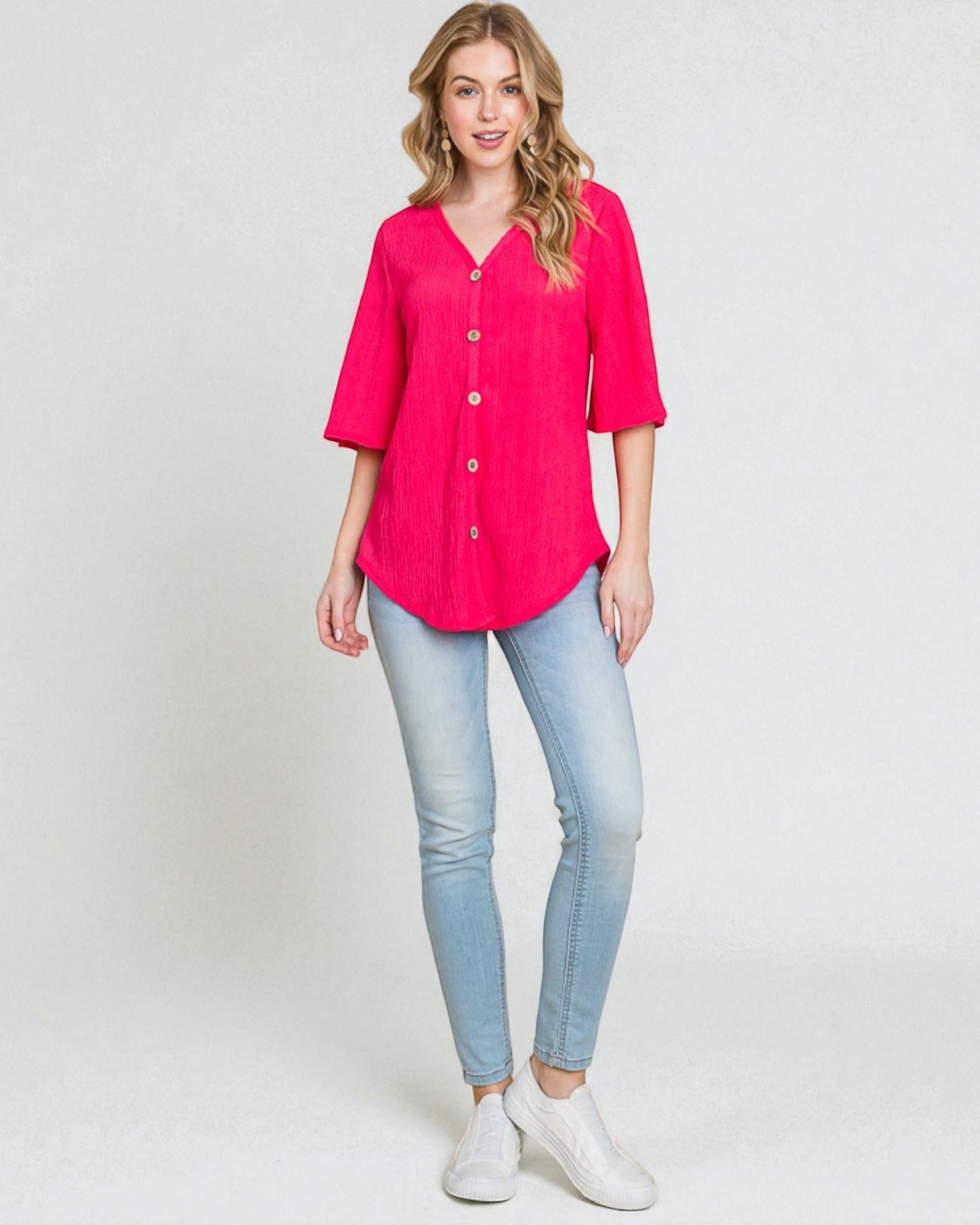 Woman wearing a bright pink blouse and light blue jeans on a white background