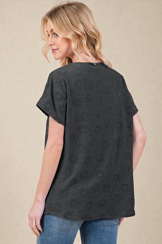 Woman wearing a black floral patterned t-shirt on a beige background