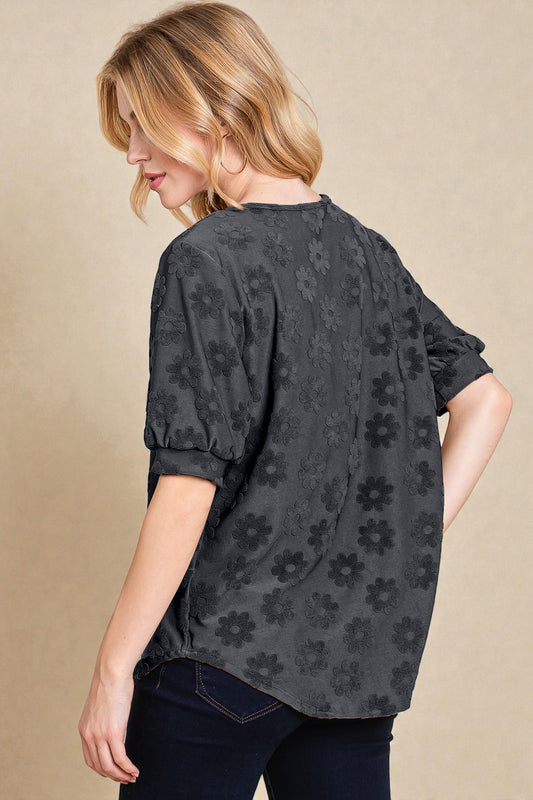 Woman wearing a dark floral patterned blouse against a beige background