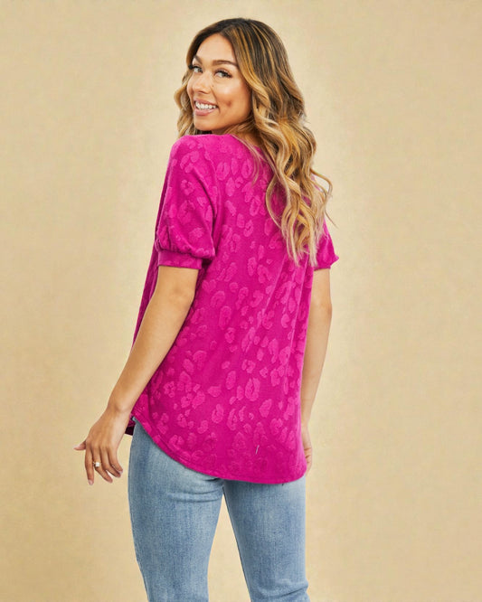 Woman wearing a pink patterned top and blue jeans against a beige background