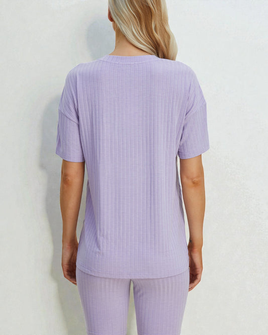 Person wearing a light purple ribbed t-shirt and pants on a white background