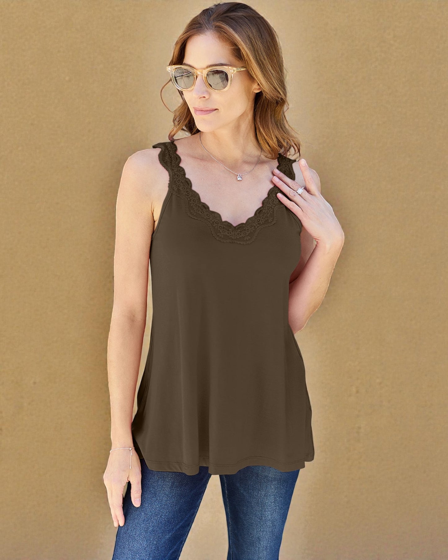 Woman wearing a brown tank top with lace details against a beige background