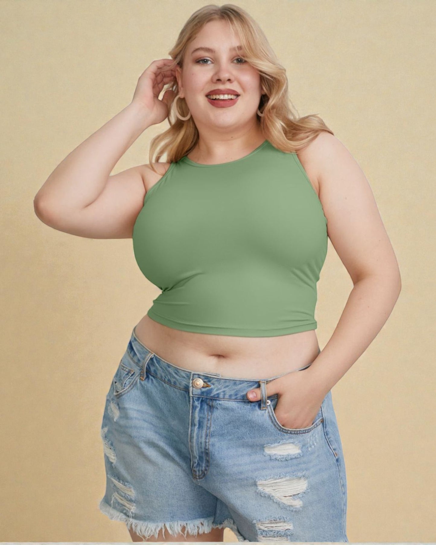Woman wearing a green crop top and denim shorts against a beige background