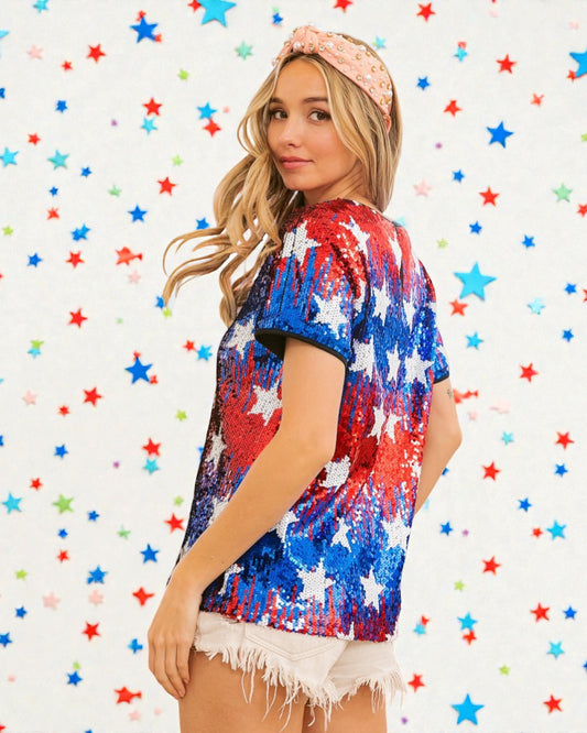 Woman wearing a red, white, and blue tie-dye shirt with a colorful star-patterned background