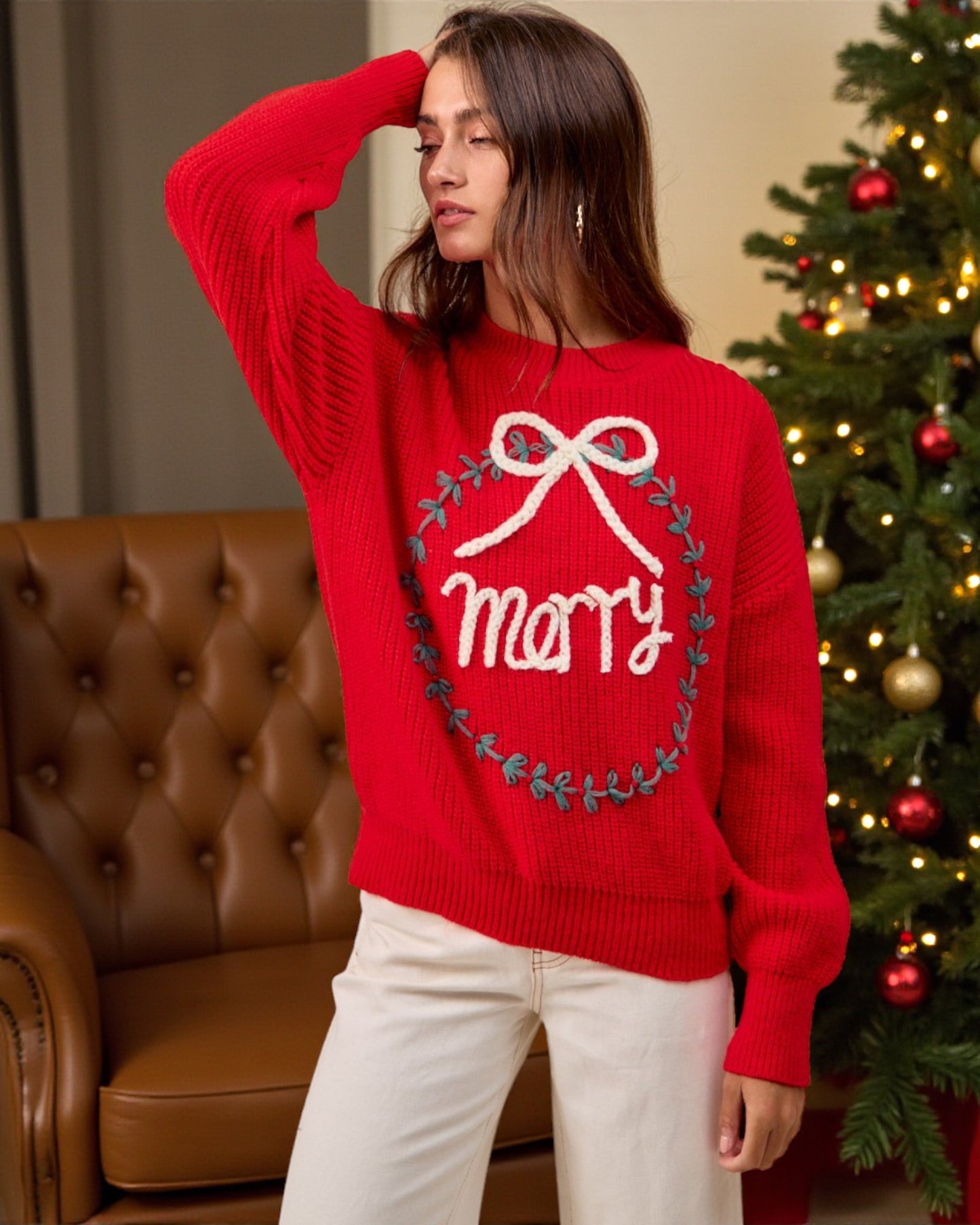 Woman wearing a red sweater with 'Merry' text in a festive setting