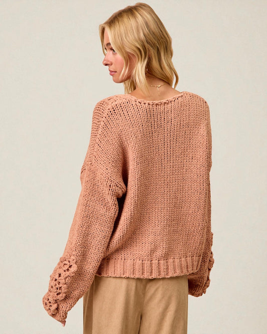 Woman wearing a pink knitted sweater on a plain background