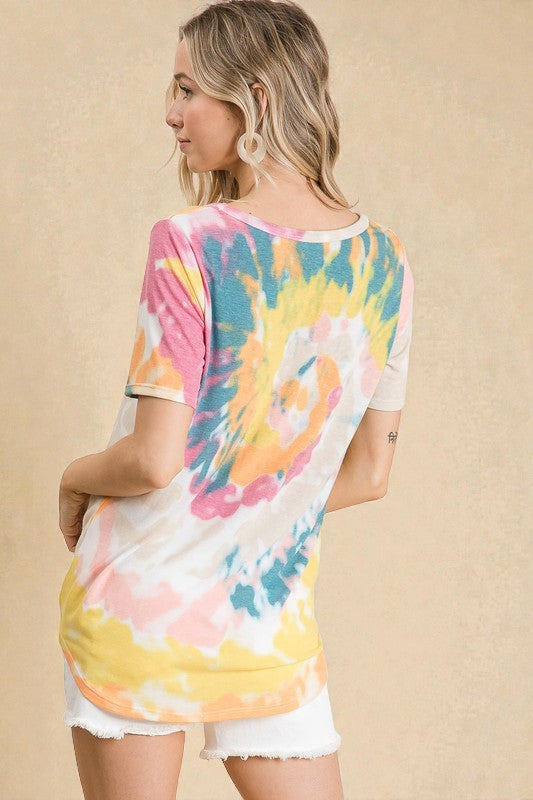 Woman wearing a colorful tie-dye shirt against a beige background