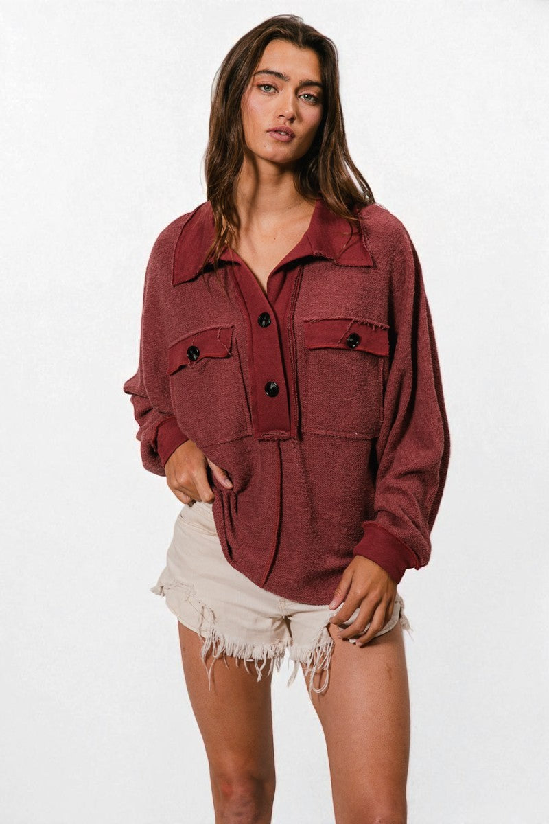 Woman wearing a burgundy jacket with black buttons on a white background