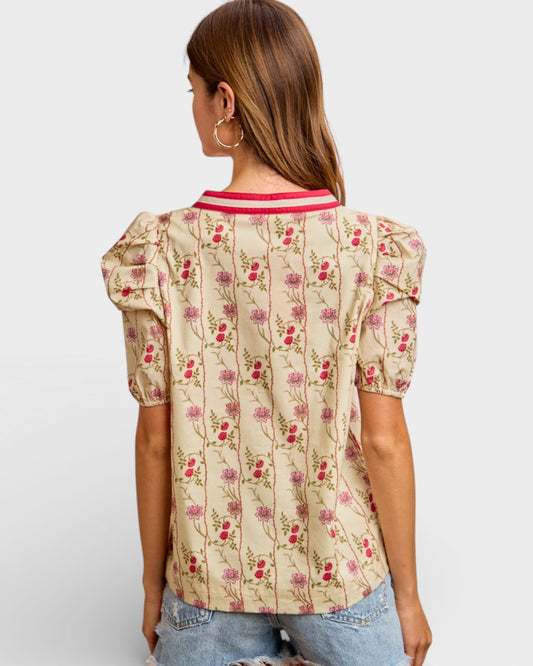 Woman wearing a floral blouse with puff sleeves on a plain background