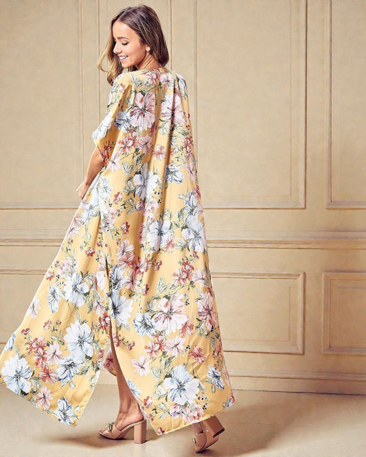 Woman wearing a long, floral-patterned dress against a beige wall.